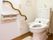 トイレの便座脇には、どちらのサイドでも手すりにつかまることができる。鏡つきの洗面台と、トイレ用のシャワーがついている。