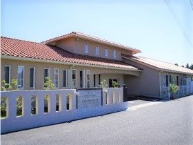 玄関を中央にして両サイドに広がっていく横に長い建物。赤い屋根がアットホームな雰囲気を演出。