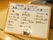 畳の上に持ち運べるサイズのホワイトボードが置かれている。ホワイトボードには、一日の献立が黒いペンで書かれている。