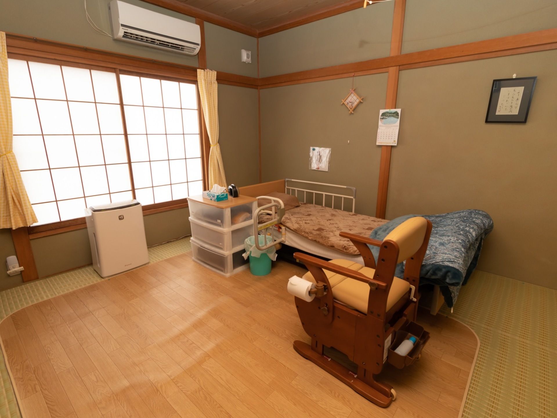 和室タイプの居室である。障子の窓にカーテンが掛けられている。畳の上には木目調のカーペットが敷かれている。