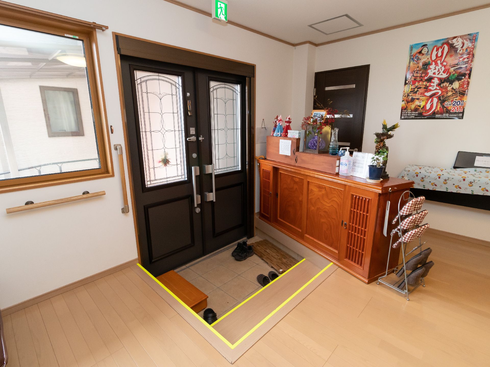 両開きの扉が設置され踏み台や目印の黄色いテープが貼られた階段のある施設玄関