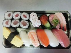 黒いプラスチック製の四角いトレーに詰められた握り寿司と巻き寿司。