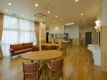 円形のテーブルセットやソファが置かれたリビングダイニング。車いす対応の洗面所やキッチンもある。