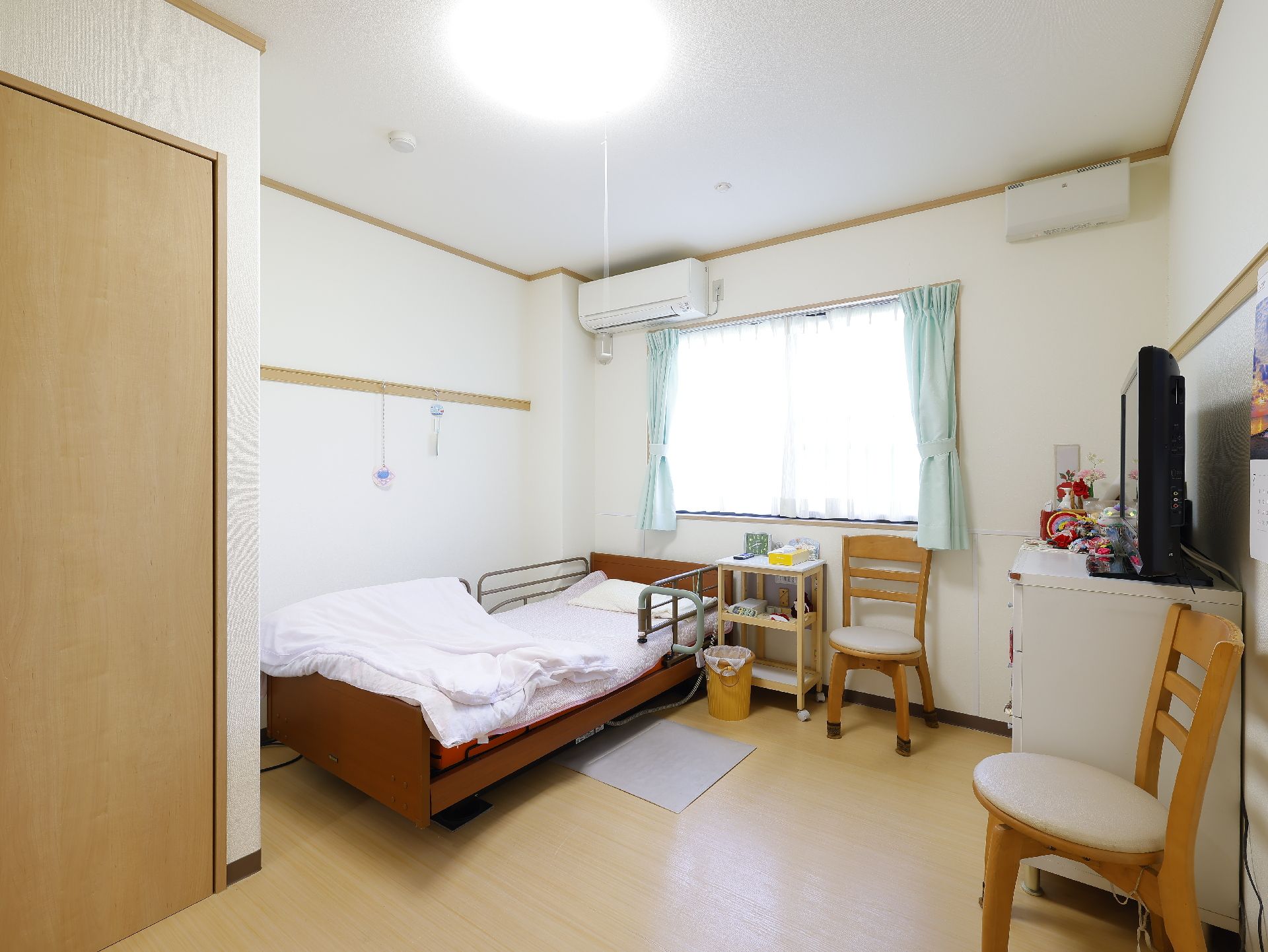 窓から光が入り、家具や介護ベッドが置かれている居室