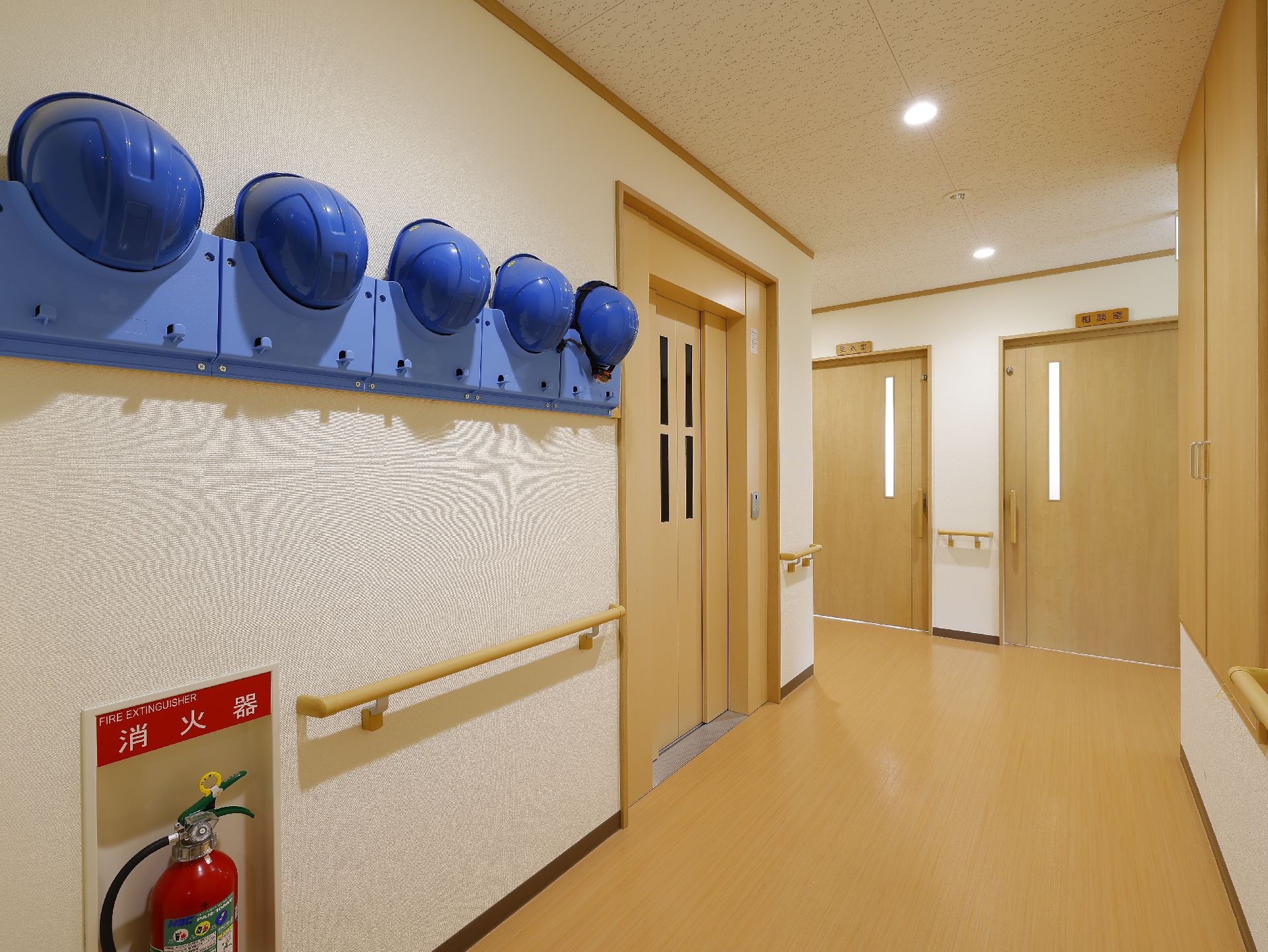 バリアフリー化され、災害用ヘルメットや消火器が設置されている廊下