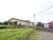 のどかな環境に建っている施設は、ゆったりとした敷地の前が滑らかな傾斜の坂道になっている。敷地の境目には垣根が植えられ施設の看板が立っている。