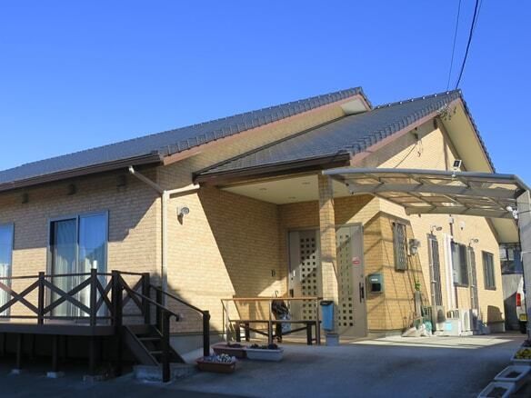 青空の下に建っている三角屋根の平屋建ての建物にはウッドデッキのテラスも設置されている。