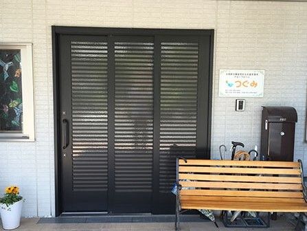施設のエントランス部分の様子。バリアフリー対応の玄関とすぐそばにある木製のベンチ