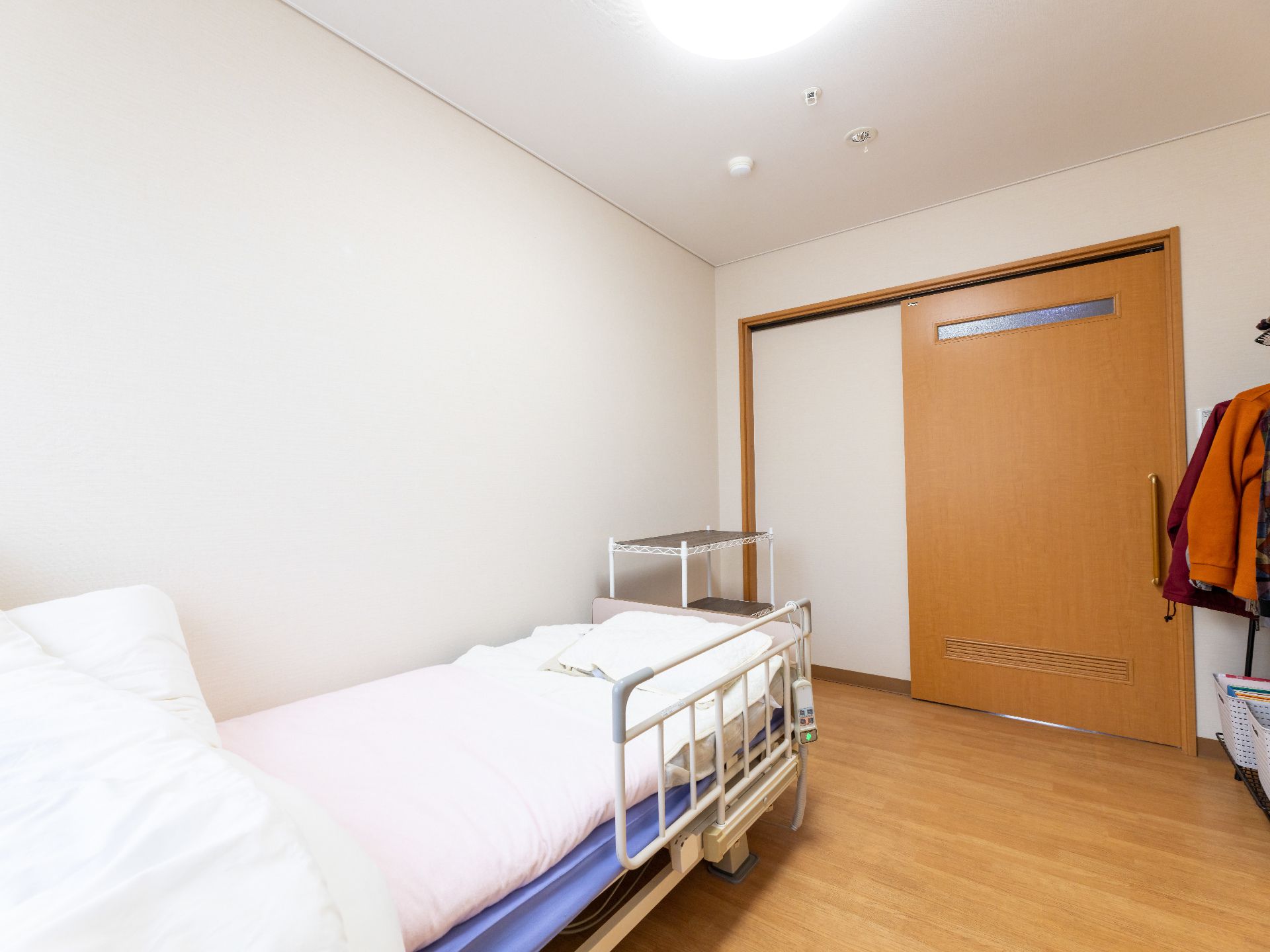 薬を飲もうとしている高齢女性と水の入ったコップを持って笑顔で待っているエプロンを付けた女性スタッフ。