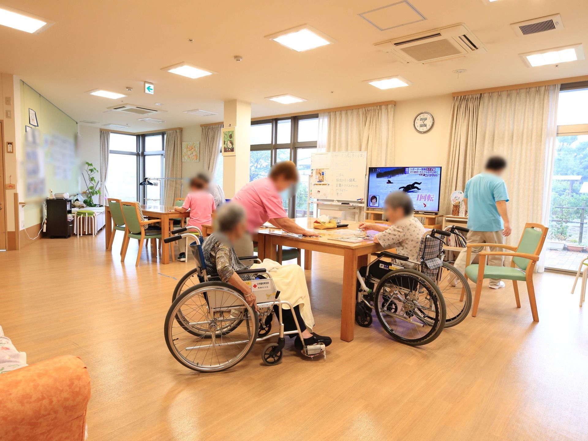 大きな掃き出し窓がある広い共有スペース。テーブルと椅子が置かれており、たくさんの人がいて、和気あいあいとした憩いの場となっている。