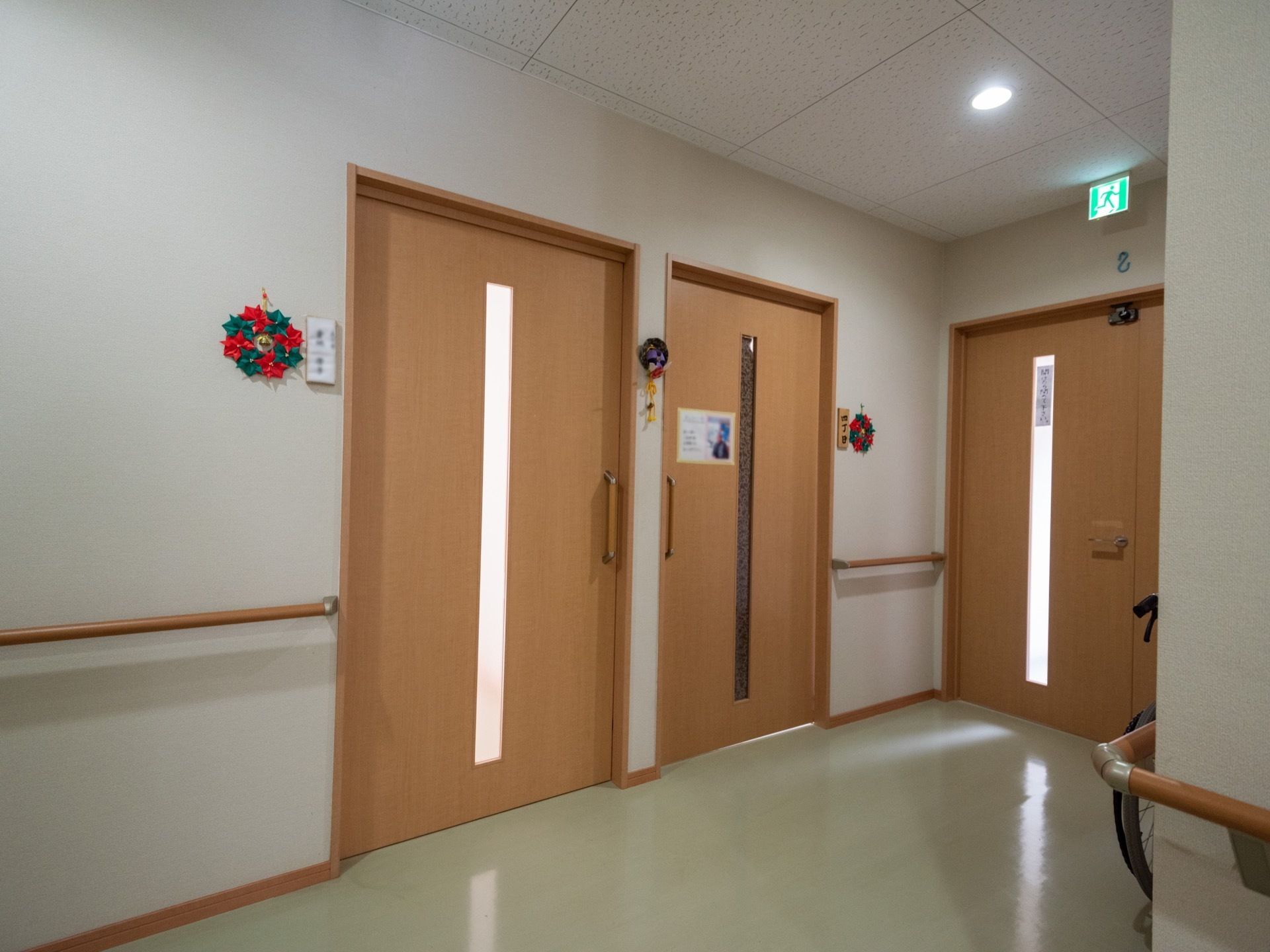 廊下の両側には手すりが備わっている。居室などの扉は引き戸になっており、その横に入居者さまのお名前が書かれたプレートが設置されている。