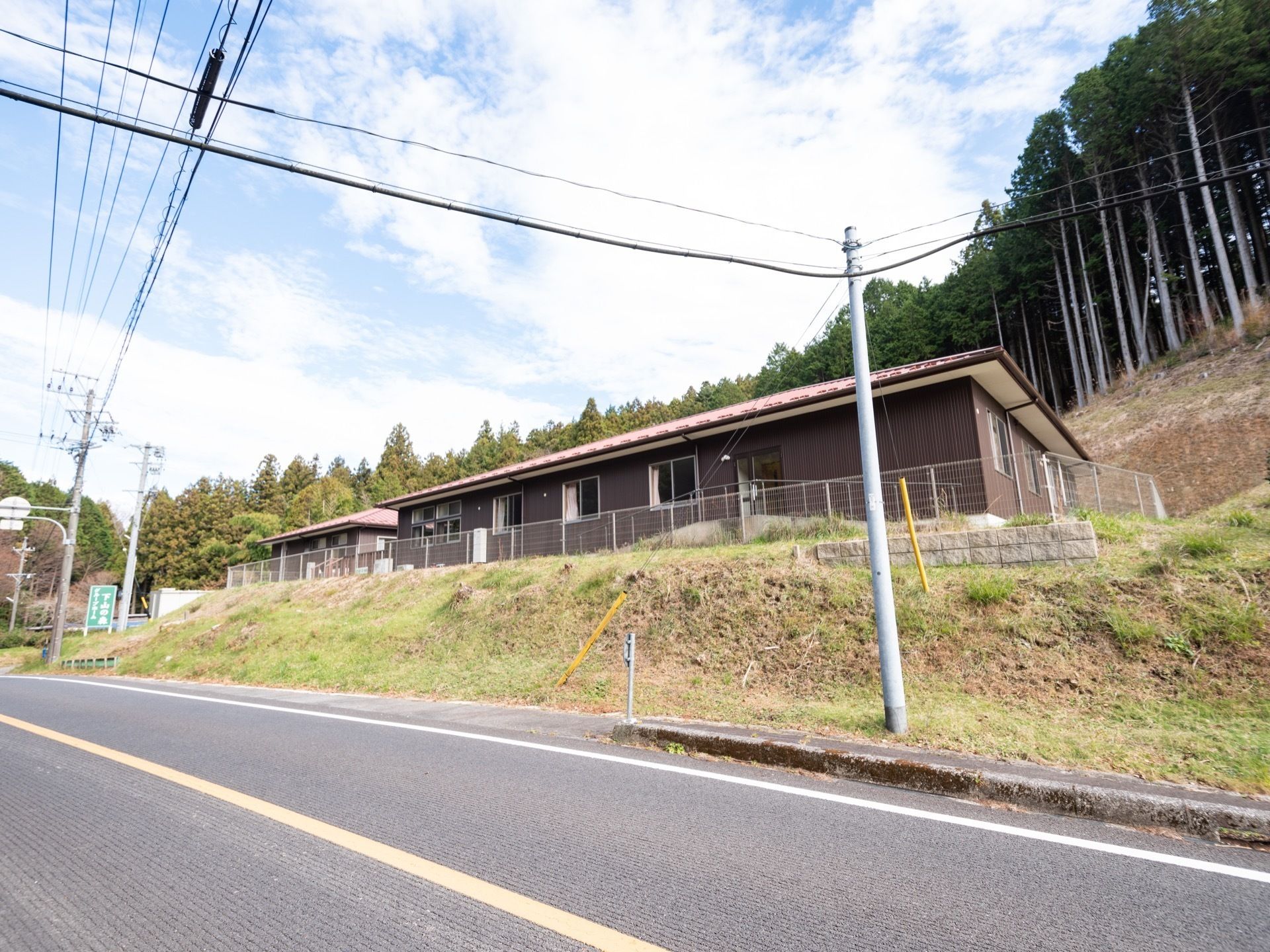 施設の周りには多くの木々が植えられている。建物はダークブラウン色の外壁になっており、落ち着いた雰囲気のデザインである。