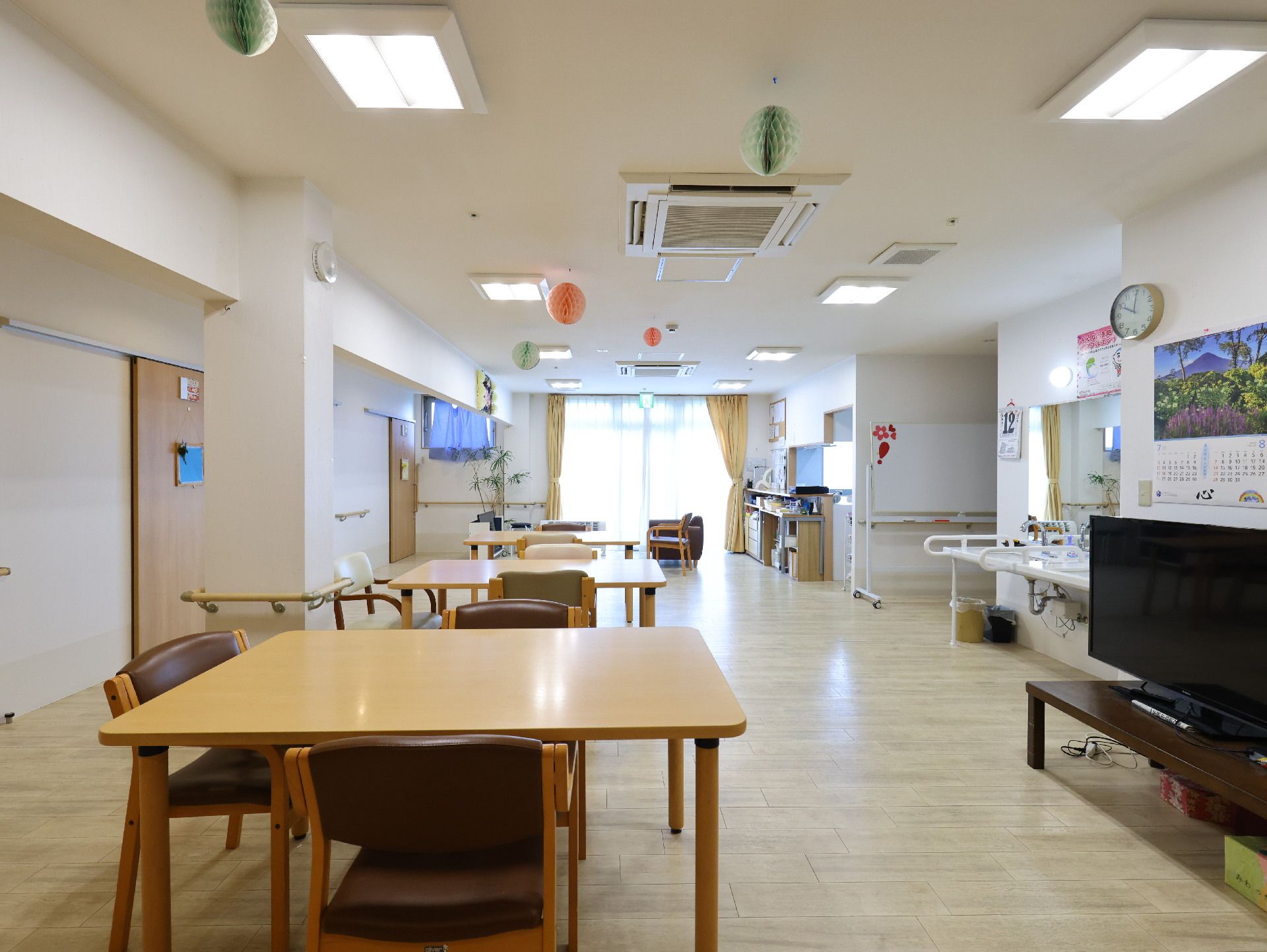 木製の机が並んだ白い壁の広間