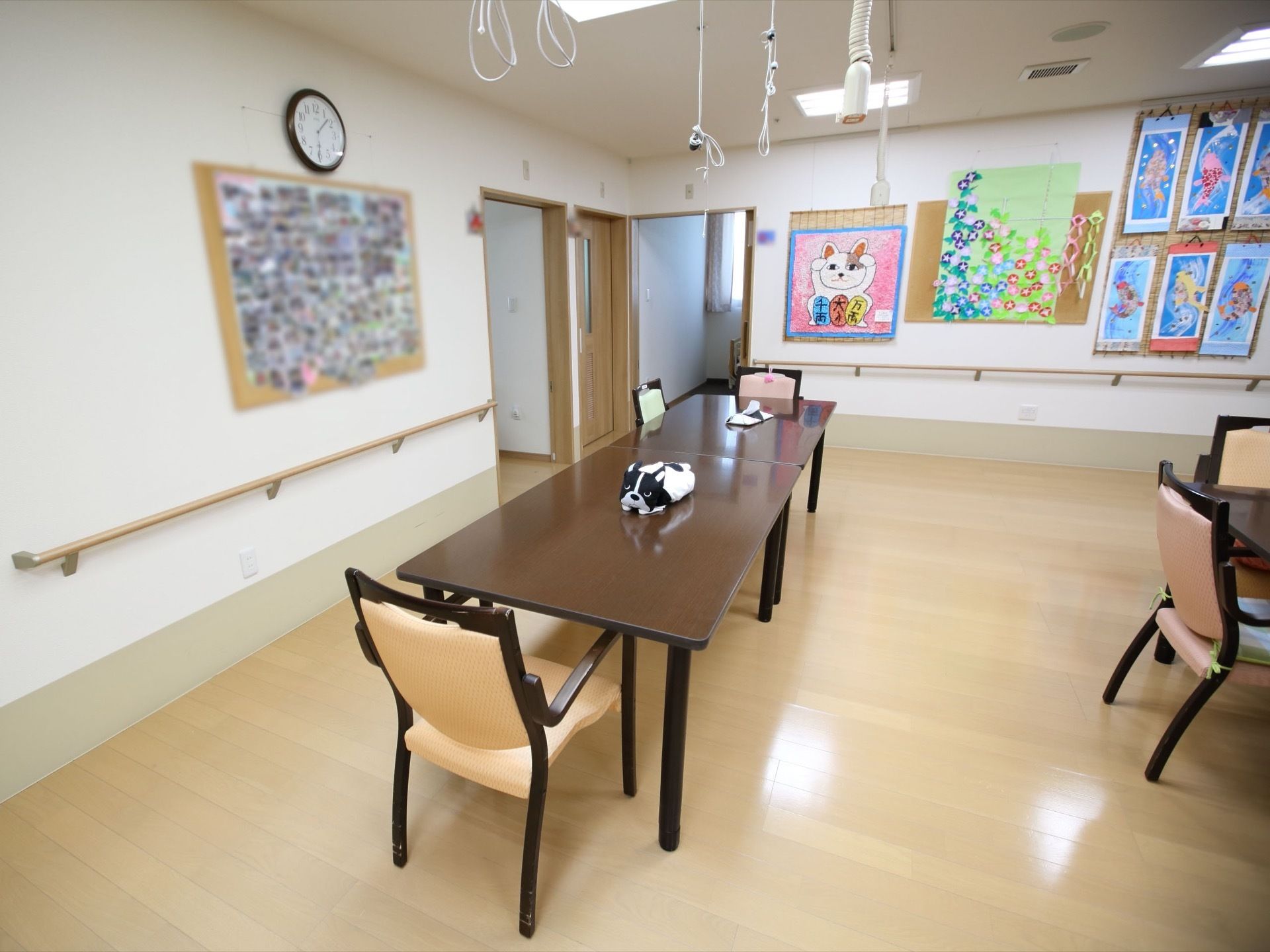 テーブルとひじ掛けの付いた椅子が置かれている食堂がある。壁には色鮮やかな絵や写真がたくさん飾られている。