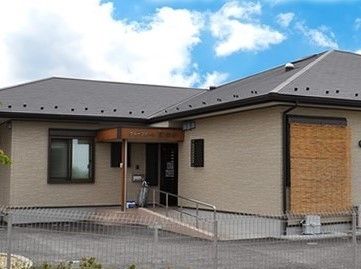 平屋建ての一軒家風の建物の写真。玄関前に車いす用のスロープが付いている様子が分かる