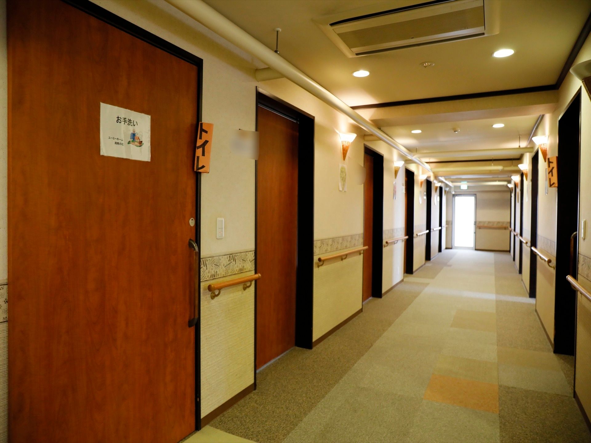 廊下の両側には居室とトイレのドアが並んでいる。トイレには、遠くからわかるよう手製の表札を突き出して張っている。