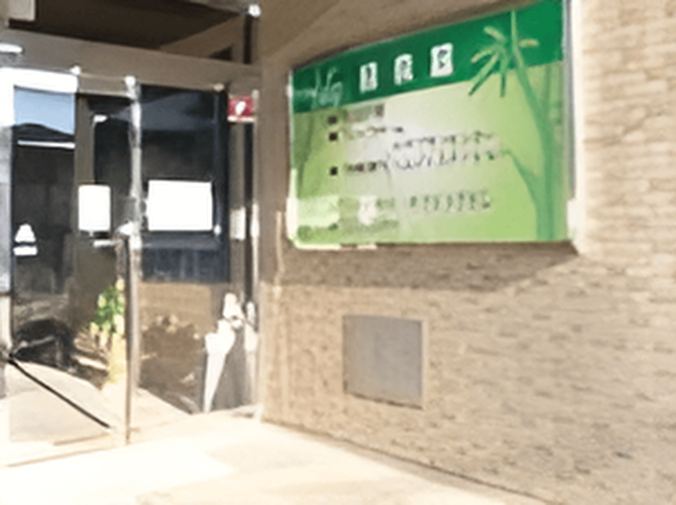 建物の玄関には段差がなく、自動ドアと、施設の案内が書かれた看板が掲げられている。
