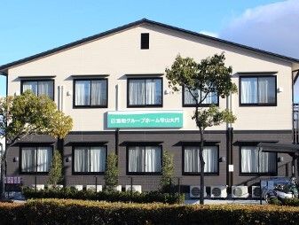 2階建ての建物は三角屋根が付き、外壁にはホーム名が書かれている。建物の周りには草木も植えられている。