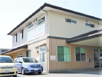 ２階建ての建物の外観写真。一軒家のような建物の前に駐車場スペースがある様子