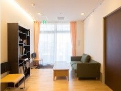 濃い色合いの家具類が置かれた施設内の居室の様子。ソファが置いてある広めの部屋