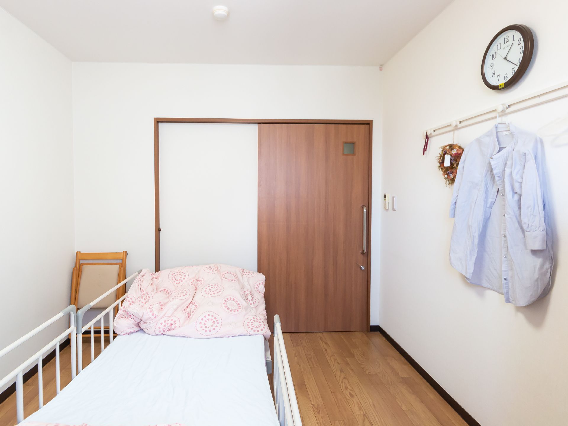 原っぱのような場所を歩いている高齢女性と付き添いのエプロンを付けた若い女性スタッフ。