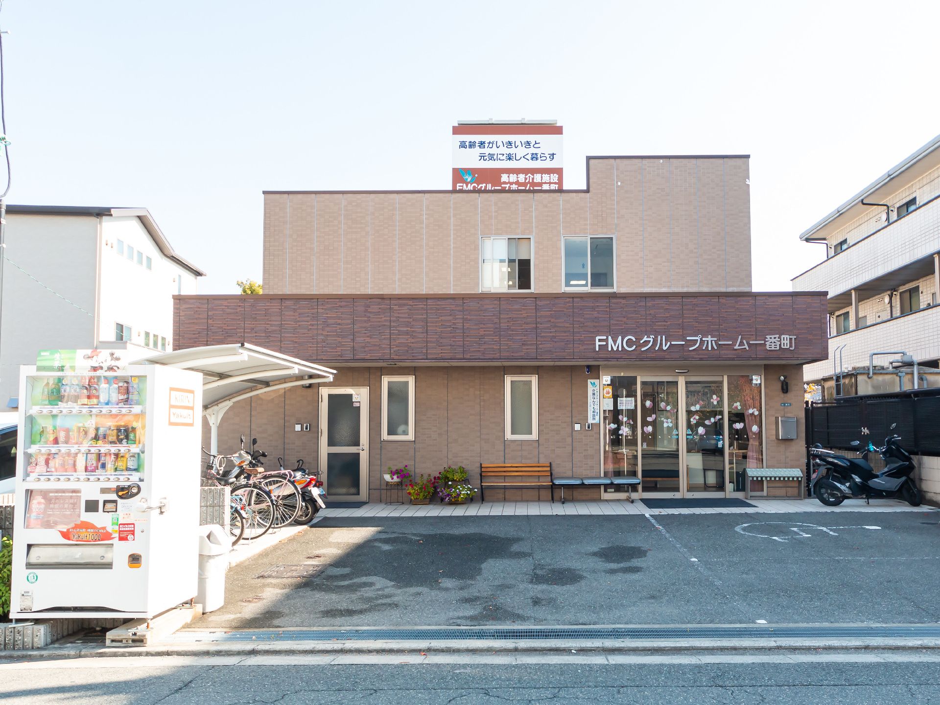 施設名前に駐輪場と自販機がある外観