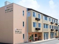 3階建ての建物は外壁にホーム名が書かれ、ベージュとブラウンで落ち着いた雰囲気。