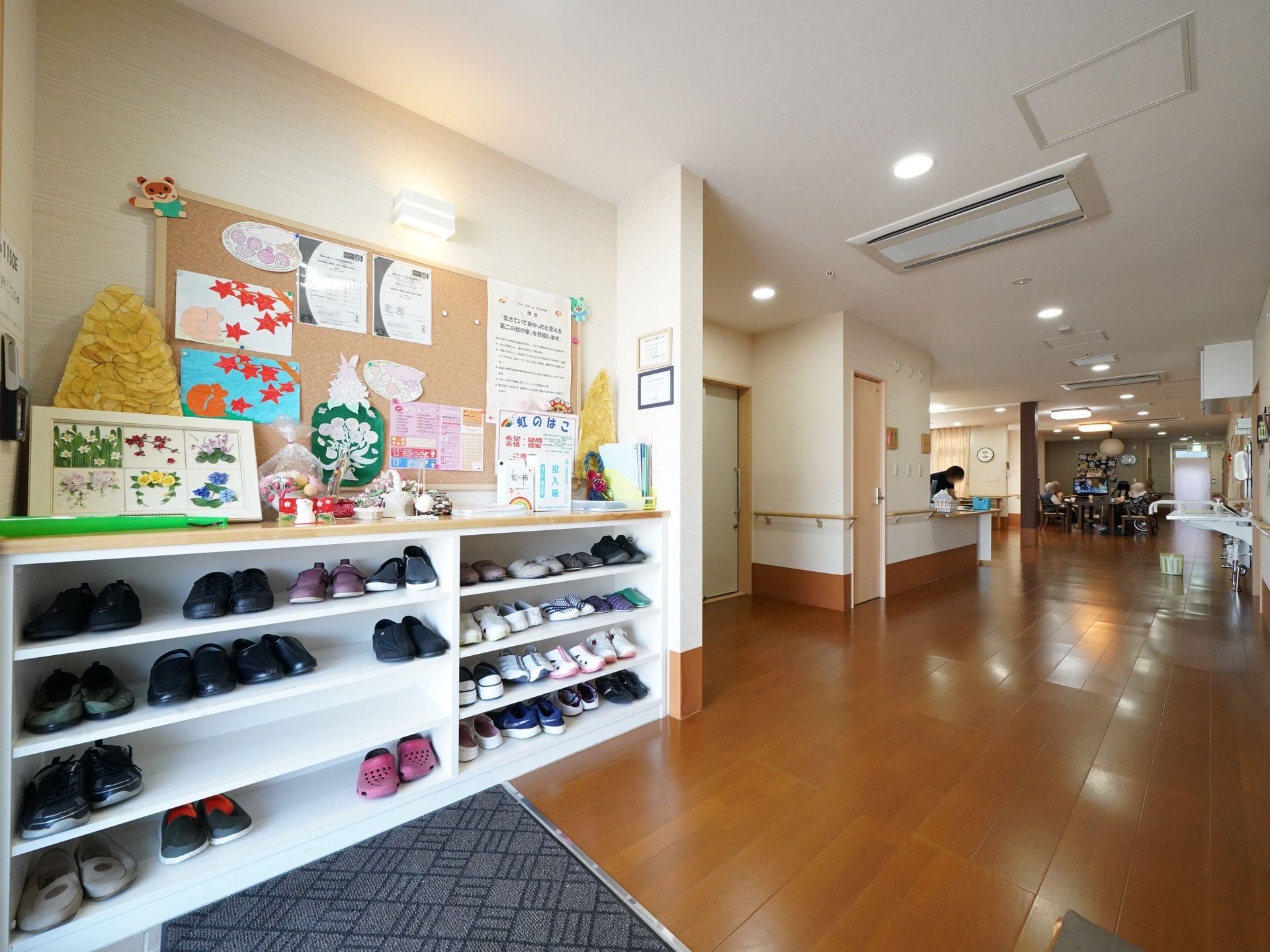 下駄箱の上にスタッフお手製の装飾物や掲示物が飾られている。床には段差がなく、壁には手すりが設置されている。