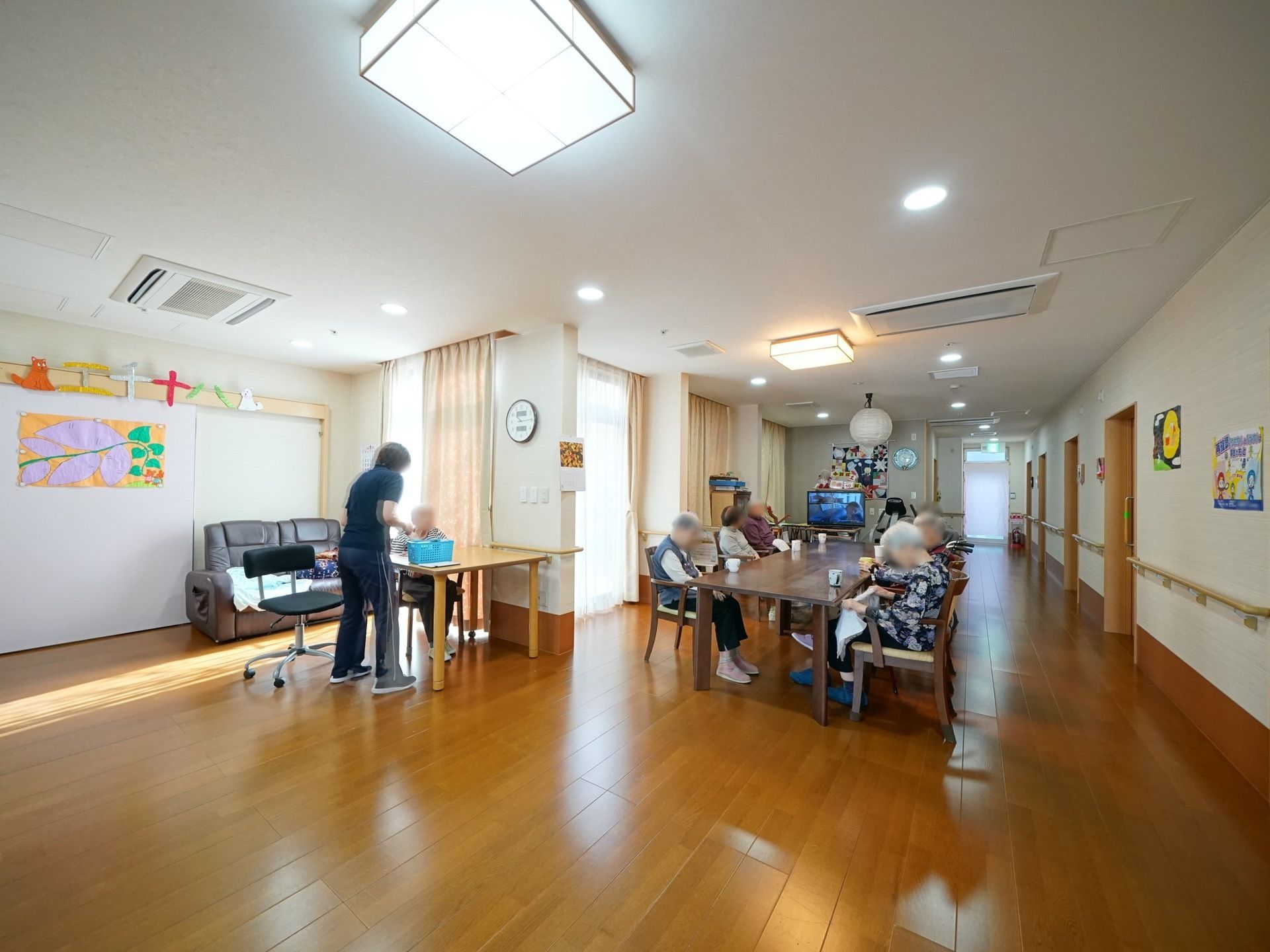 広々としたフローリングになっている。壁には入居者様の作品が飾られている。テレビがあり、鑑賞をお楽しみいただける。