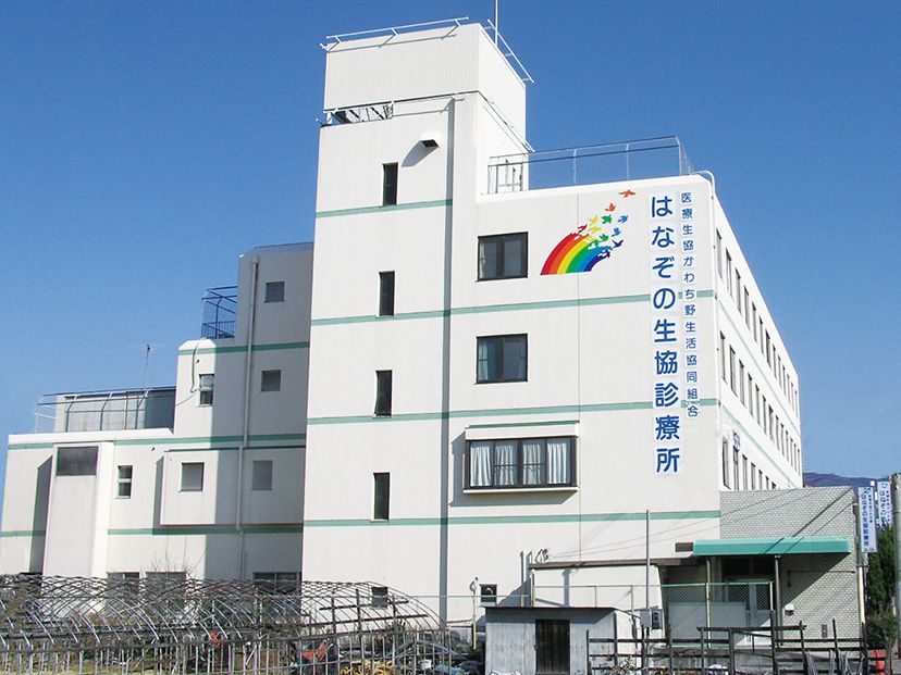 真っ白な４階建ての建物にはブルーのラインが入っている。右上に診療所の名前が書かれている。