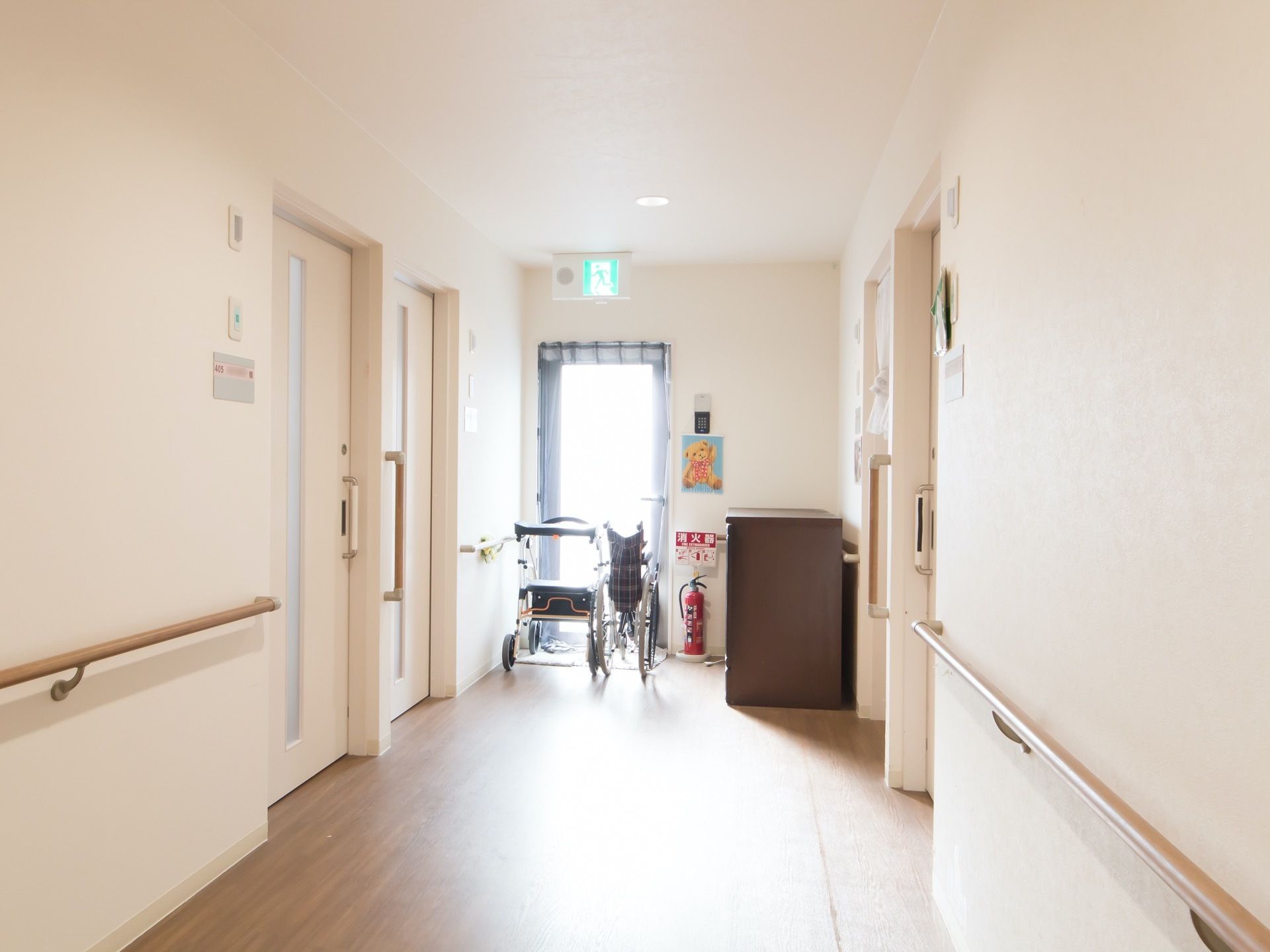 白を基調とした明るい廊下である。突き当たりには非常口が設けられており、消火器や車椅子がある。
