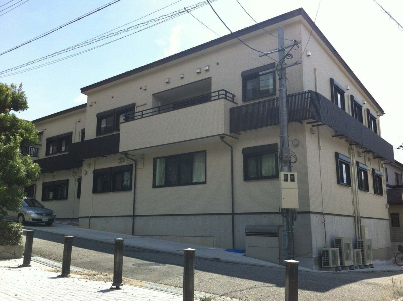 ベージュ系の2階建ての建物は日当たりのいい場所に建っていて、坂道がホームの前にある。