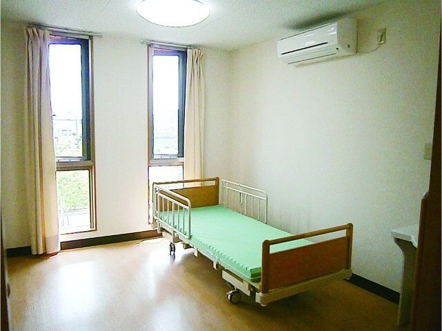エアコンとベッドが映っている居室の様子。盾形の窓がある部屋