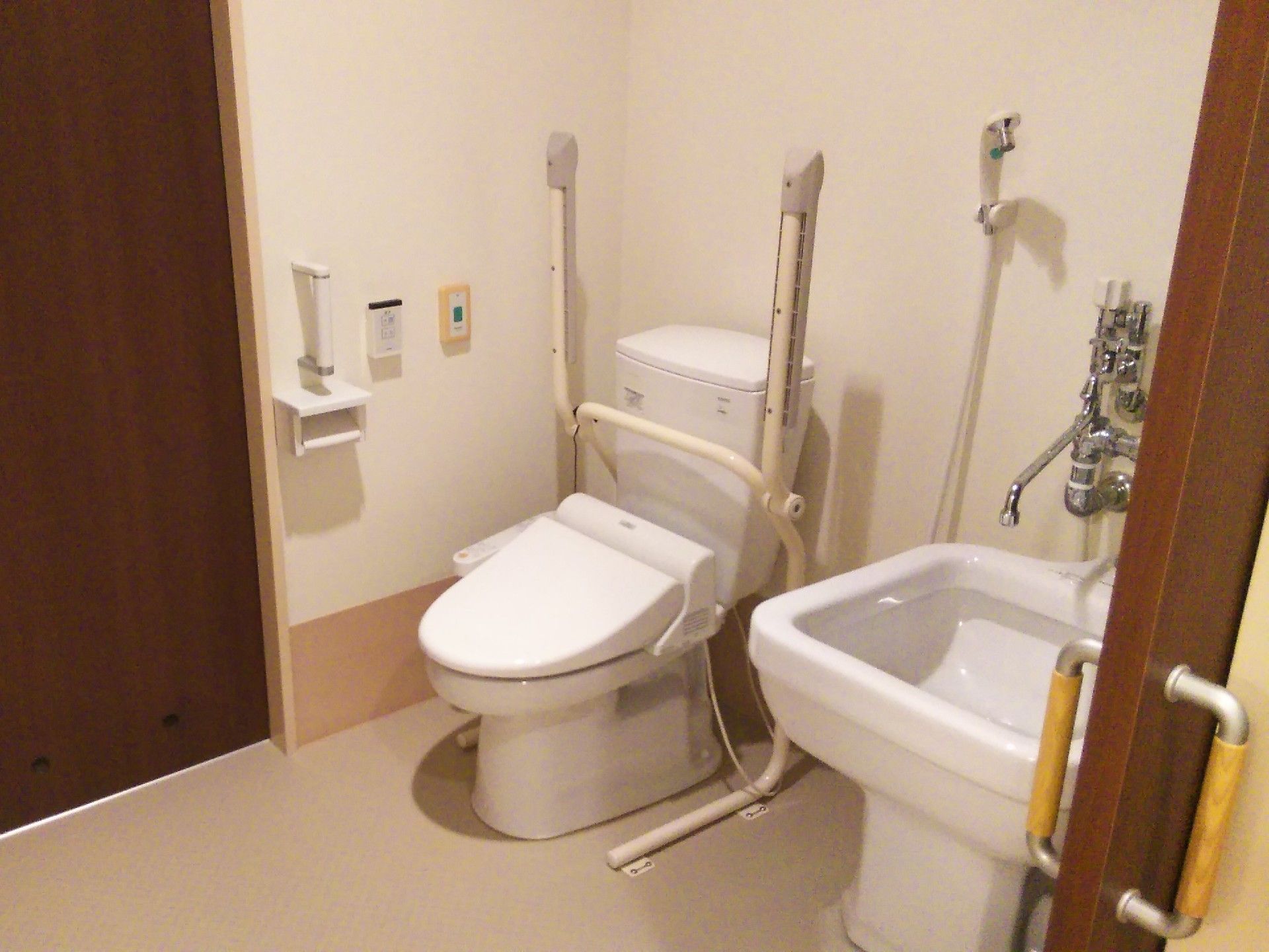 白いトイレの右には呼び出しボタン、左には洗い場などがある。両サイドから出入りができる。
