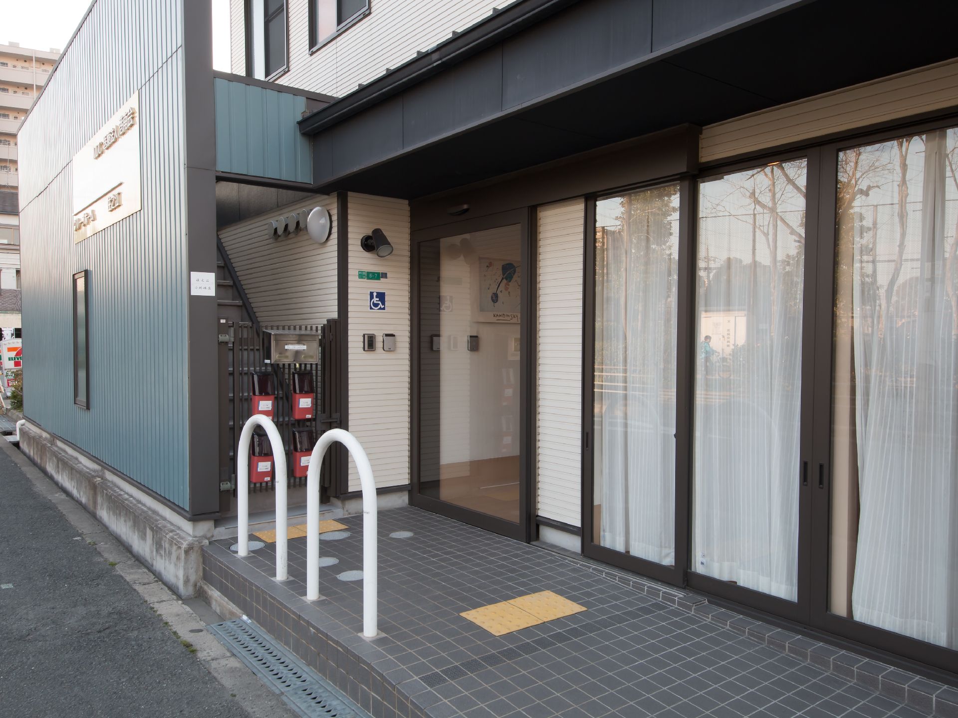 駐車スペースから玄関までの通路は、スロープになっている。手すりや点字シート、幅のある大きな自動扉が設置されている。
