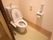 温水洗浄便座が設置されたトイレである。手すりとケアコールが設置されている。入口のドアは引き戸である。