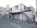 白い壁にブラウンのサッシがシンプルな、２階建ての施設建物である。２階から１階地上へと、非常階段が設置されている。