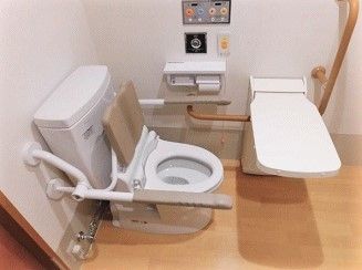 両側に手すりがついている施設内のトイレの様子。立ち上がり用の大きめの手すり、緊急コールがついている
