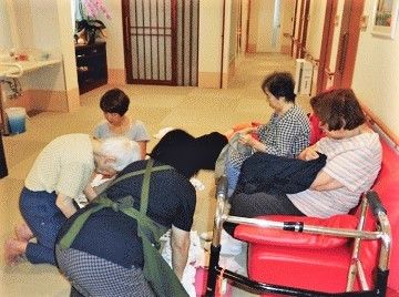 施設内の共有スペースに座っている高齢者とスタッフの様子。リラックスタイムの一場面