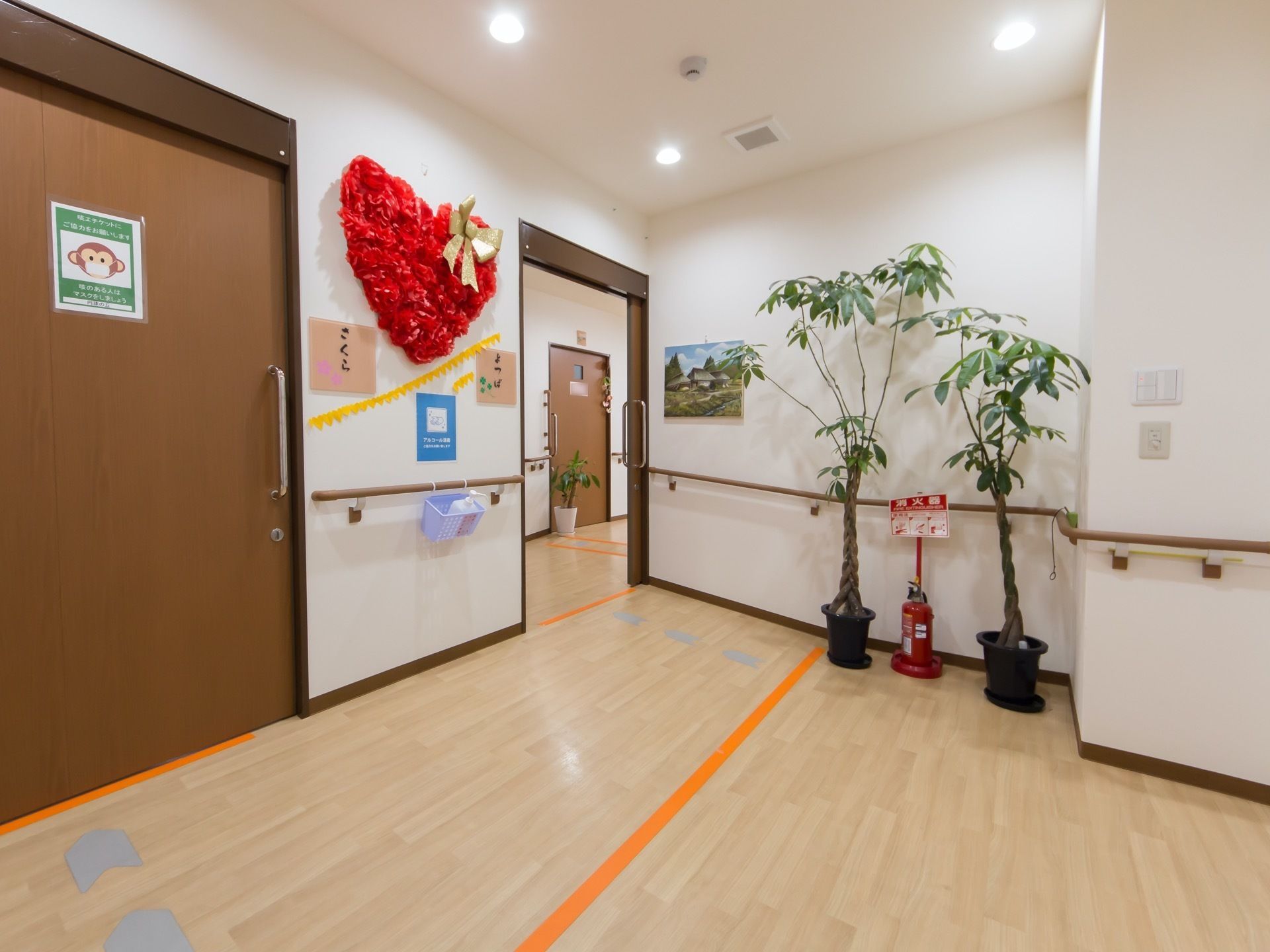 通路には、観葉植物や消火器が配置されている。レイアウトされた白い壁には、途切れることなく手すりが設置されている。