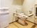 広いトイレには手すり付きのトイレと手洗い場があり、便器にはふたが付いていない。