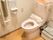 温水洗浄機能付きのトイレがある。床はフローリングで、便座の近くには手すりとナースコールが備え付けられている。