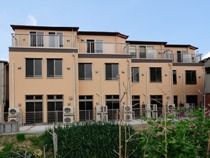 自然に囲まれたのどかな立地にある３階建てのブラウンの建物。