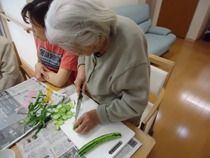 食堂のテーブルで野菜を刻んでいるスタッフ。すぐそばにスタッフがいる。