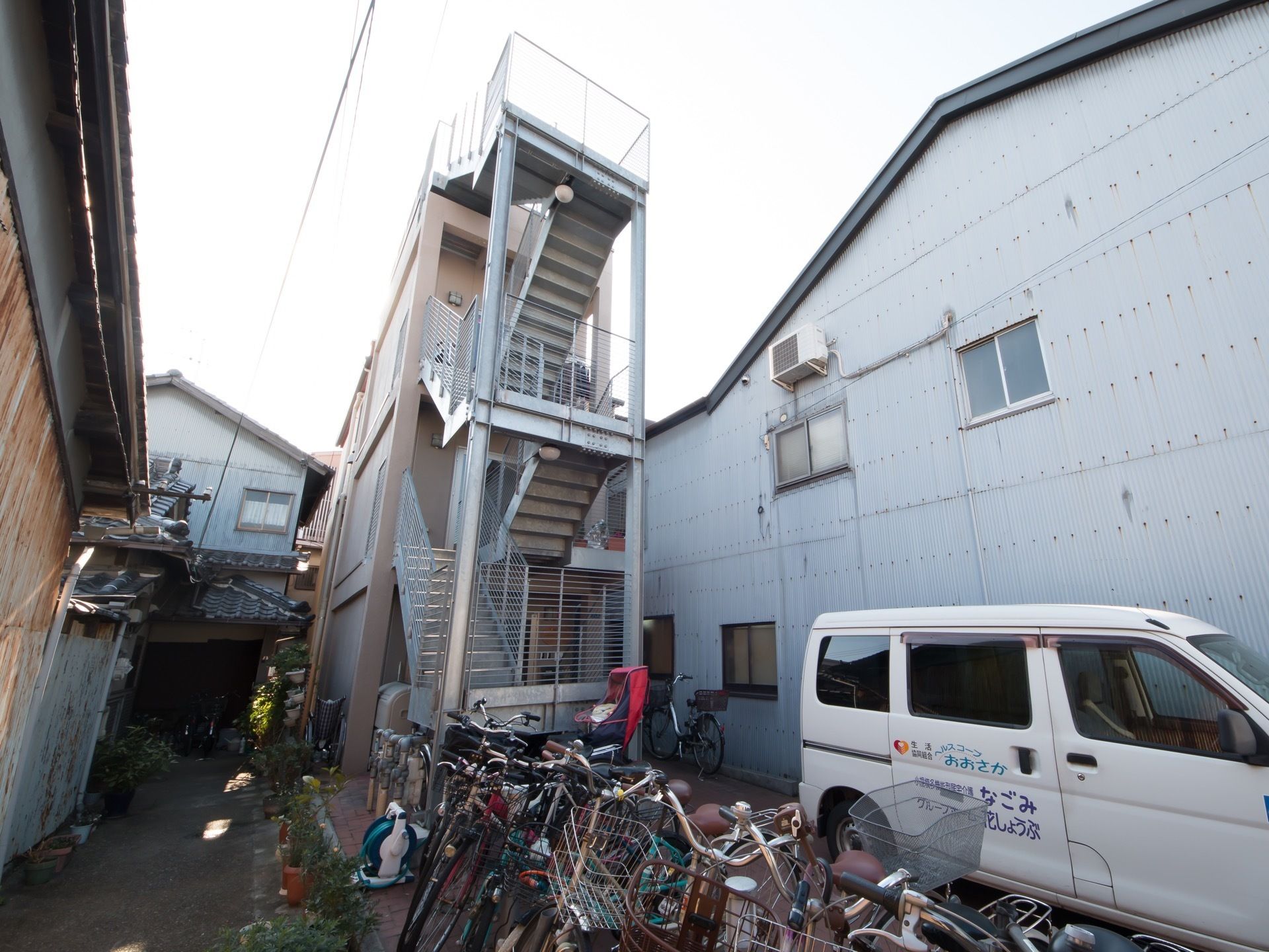 道路から奥まった所に建っている３階建ての施設である。しっかりとした手すりや柵がついた非常階段が設置されている。
