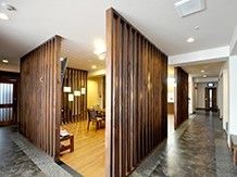 回廊式の廊下は落ち着きのある雰囲気。共有スペースが木目調の壁で仕切られ、いすやテーブルが置かれている。