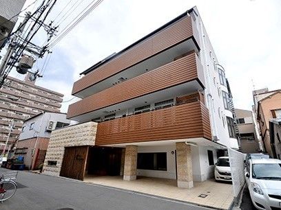 ４階建ての建物はブラウンを基調とした重厚感のある造り。駐車スペースもある。