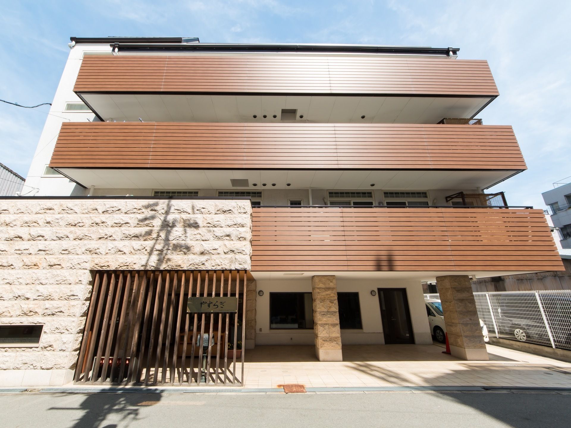 広々としたベランダ付きの、４階建ての施設外観である。玄関は道路から奥まったところにあるので、出入りの際も安心である。
