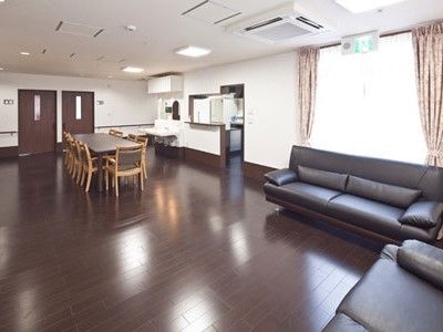 右にはソファが並んだリビングスペース、左奥にはダイニングスペースやキッチンがある。ブラウンを基調とした大人の雰囲気。