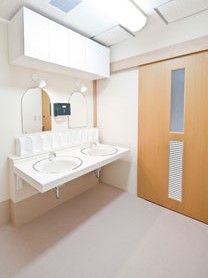 洗面所が二つ並び、それぞれに鏡付いている。左手に引き戸のドア。